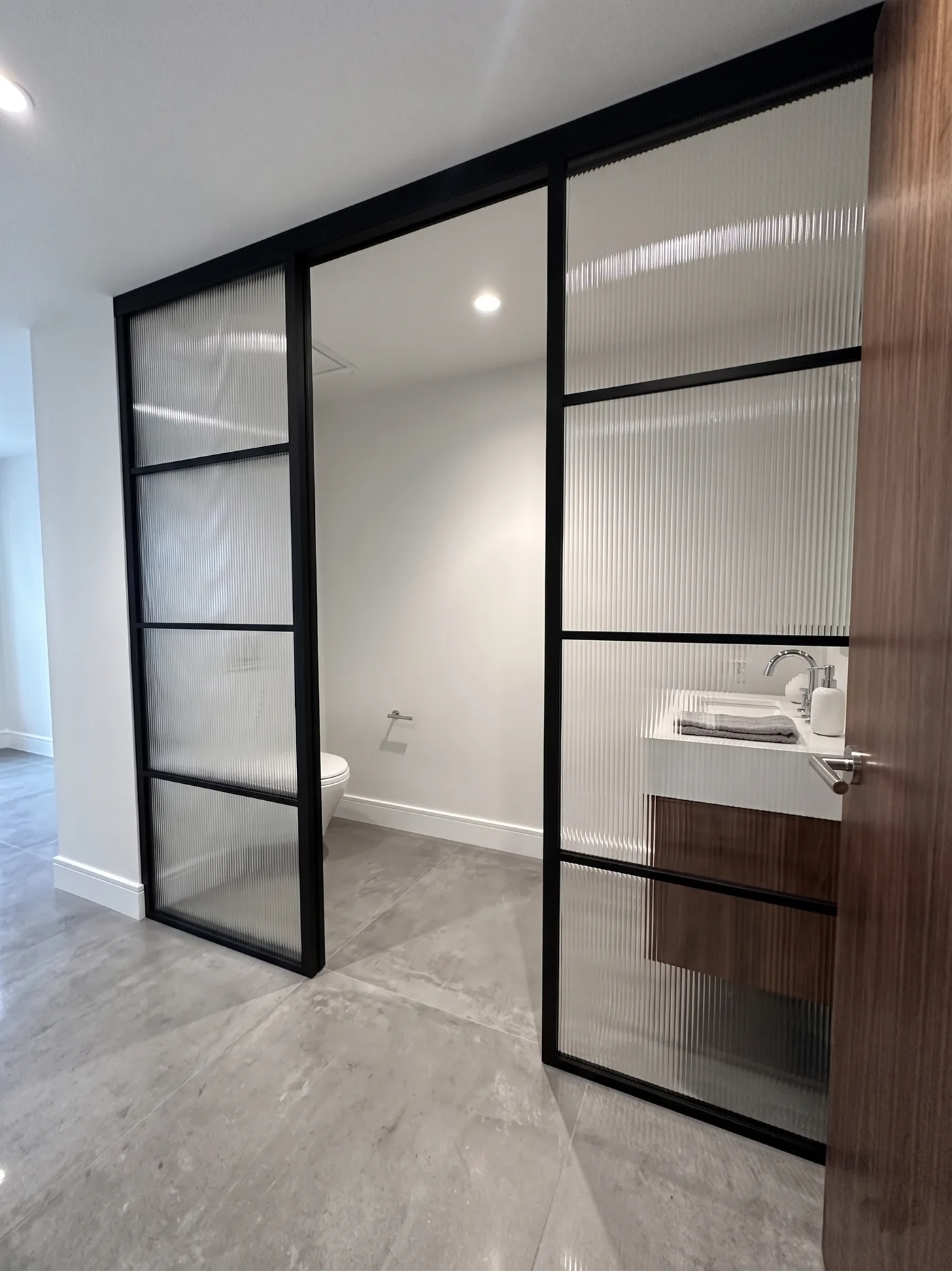 Reeded glass sliding partition enclosing a powder room
