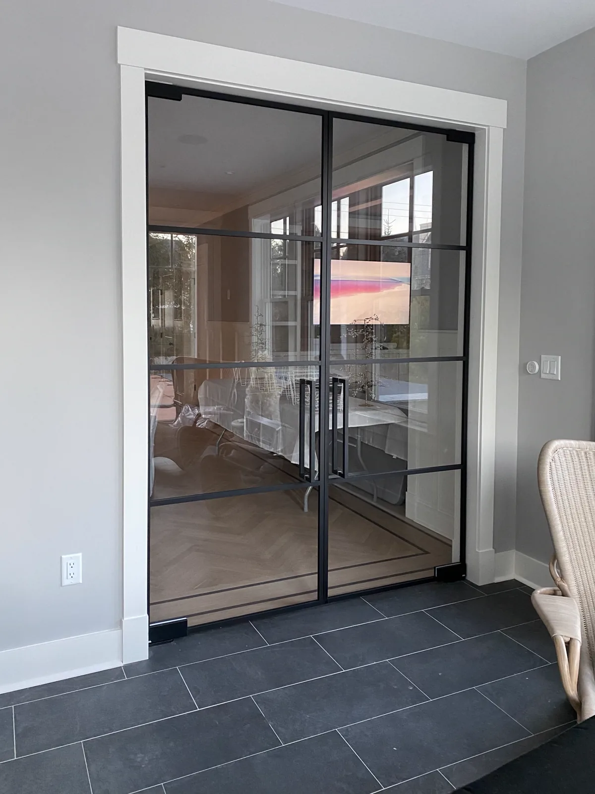 A pair of gray tinted glass doors in black frames closed across a dining room opening