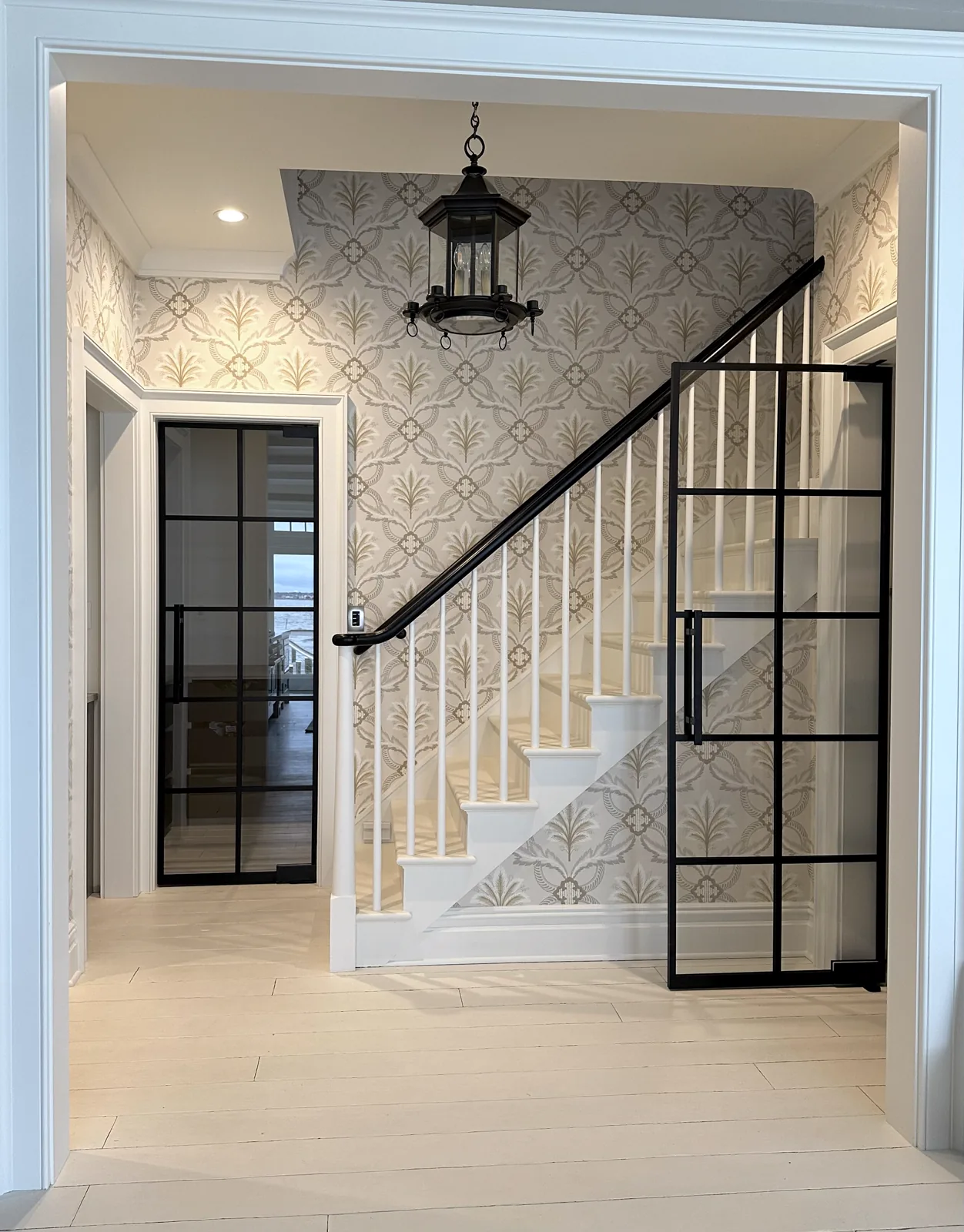 Glass door enclosing a staircase landing with a black grid frame